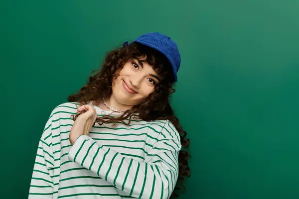 A young woman with curly hair expresses joy while posing against a vibrant green backdrop. — Stock Photo