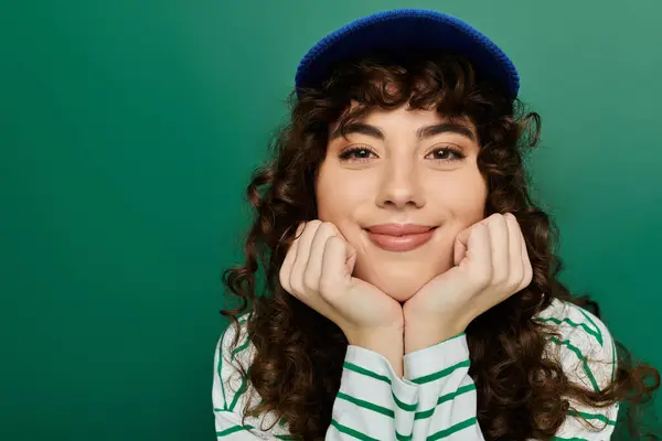 A young woman wearing a striped shirt and blue cap shows her joyful emotions through a bright smile. — Stock Photo