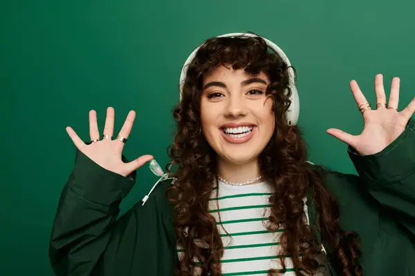 Stylish woman with curly hair showcases excitement while wearing headphones, embracing the moment. — Stock Photo