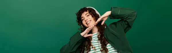 Stylish woman with curly hair joyfully posing with playful gestures in a modern setting. — Stock Photo
