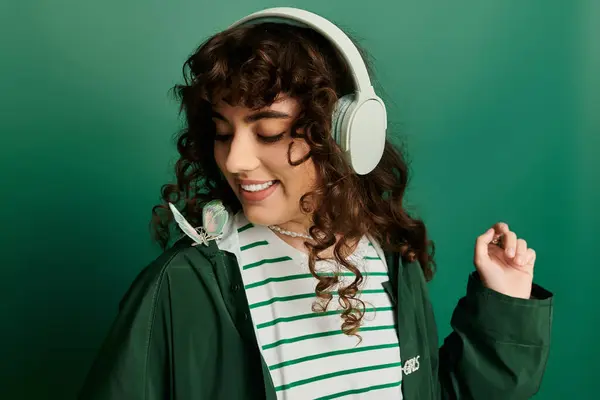 L'emozione brilla mentre una giovane donna alla moda indossa le cuffie, sorridendo con una farfalla nelle vicinanze. — Foto stock