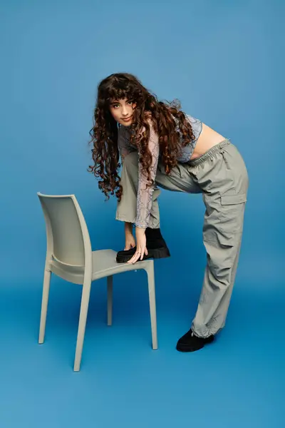 Young woman with curly hair shows off her trendy outfit in a playful, creative pose. — Stock Photo
