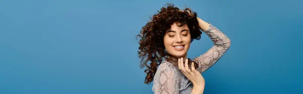 Giovane donna sicura di sé con i capelli ricci sorride brillantemente in un vestito chic. — Foto stock