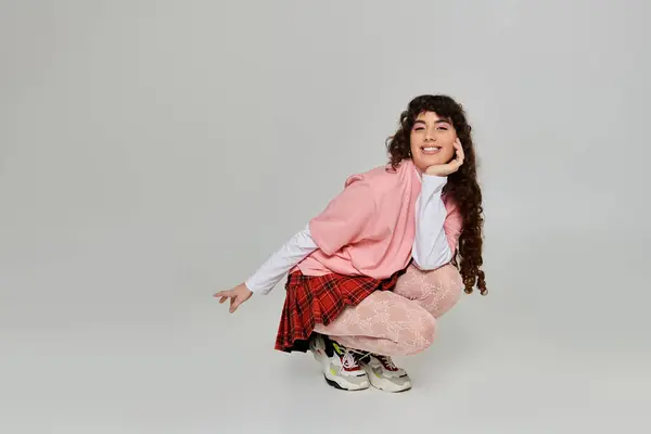 Young woman with curly hair showcases her fashion sense in a playful pose during a photoshoot. — Stock Photo