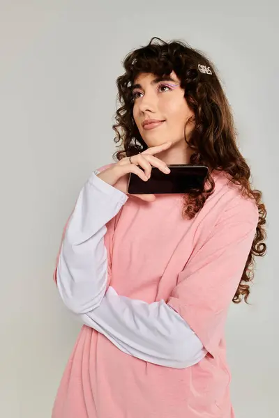 A fashionable young woman gazes thoughtfully while holding her smartphone, radiating emotion. — Stock Photo