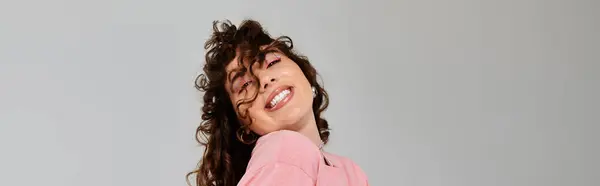 Young woman in a pink outfit beams with joy, showcasing her lively curls. — Stock Photo