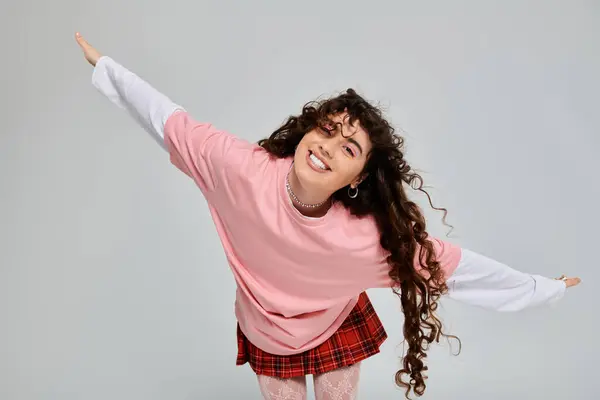Una joven con el pelo rizado viga alegremente en su elegante y despreocupado atuendo. - foto de stock