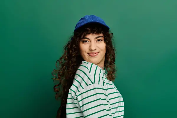 Young woman wears a striped shirt and cap while expressing her emotions with a playful smile. — Stock Photo