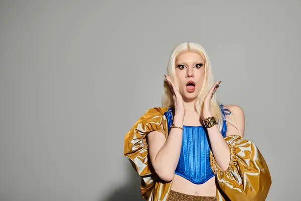 A chic drag queen showcases a bold look, striking an expressive pose against a plain backdrop. — Stock Photo