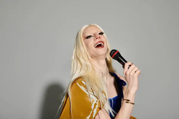 Questa elegante giovane drag queen canta fiduciosa in un microfono, trasudando energia vibrante. — Foto stock