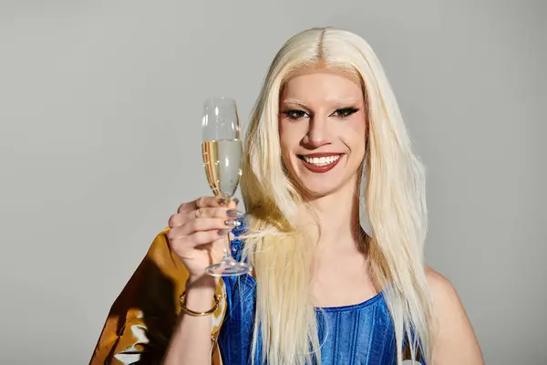A dazzling young drag queen raises a glass of champagne, radiating vibrant style and confidence. — Stock Photo