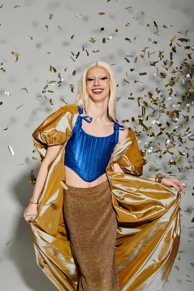 Stylish young drag queen twirls gracefully in a chic outfit, surrounded by shimmering confetti. — Stock Photo