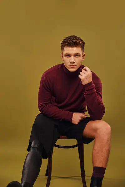 Um jovem com uma perna protética modela uma roupa moderna, exalando confiança em um estúdio. — Fotografia de Stock