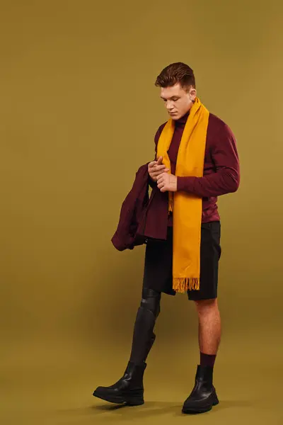 Un joven con estilo posa en un estudio, mostrando su atuendo y su pierna protésica. - foto de stock