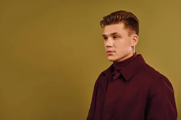 Un jeune homme élégant en manteau pose avec confiance dans un cadre de studio. — Photo de stock