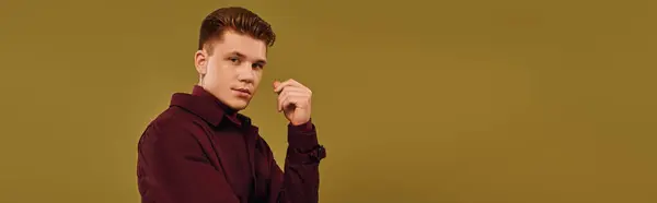 A stylish young man poses confidently against a warm backdrop, radiating charm. — Stock Photo