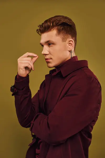 A handsome young man showcases his trendy outfit with a thoughtful pose in a studio. — Stock Photo