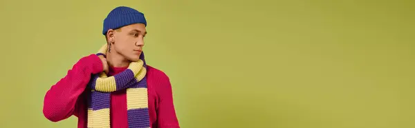 A handsome young man displays trendy winter attire while posing confidently on bright green background, banner — Stock Photo
