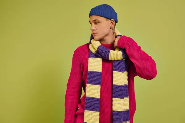 Young model displays trendy winter attire with a colorful scarf against a bright background. — Stock Photo