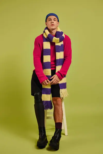 Fashionable young man showcases trendy attire in a vibrant studio while posing confidently. — Stock Photo