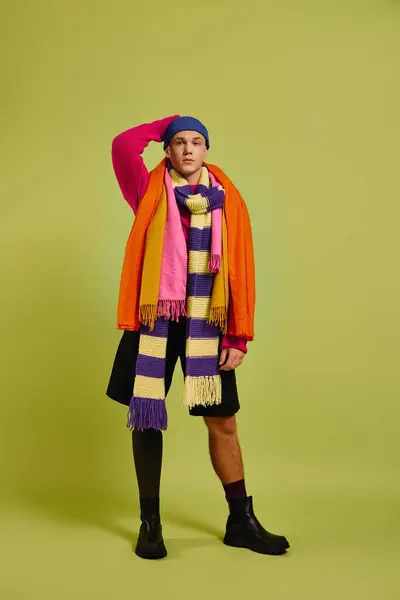 Um jovem bonito posa confiantemente em trajes da moda com um lenço colorido em um estúdio. — Fotografia de Stock