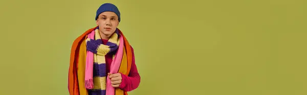 Young man sports vibrant, fashionable layers of clothing in a stylish studio setting, banner — Stock Photo