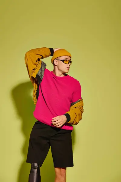 O jovem com uma perna protética posa confiantemente no traje na moda contra um contexto brilhante. — Fotografia de Stock