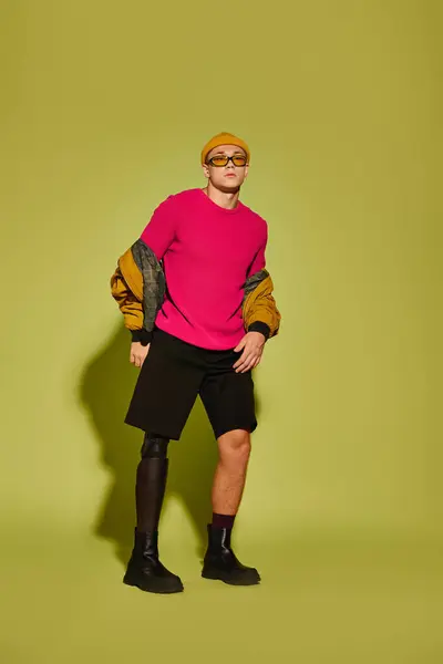 Um jovem elegante confiantemente modela roupas da moda em um estúdio vibrante com sua perna protética. — Fotografia de Stock
