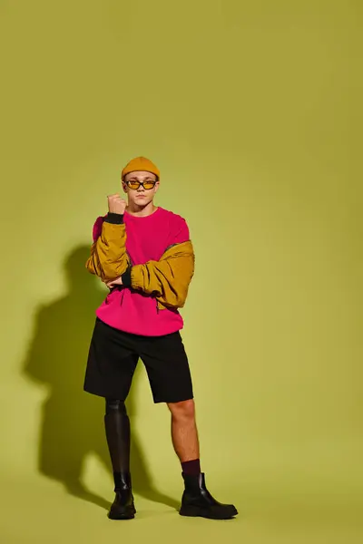 Un joven con ropa elegante muestra con confianza su pierna protésica, celebrando la diversidad. - foto de stock
