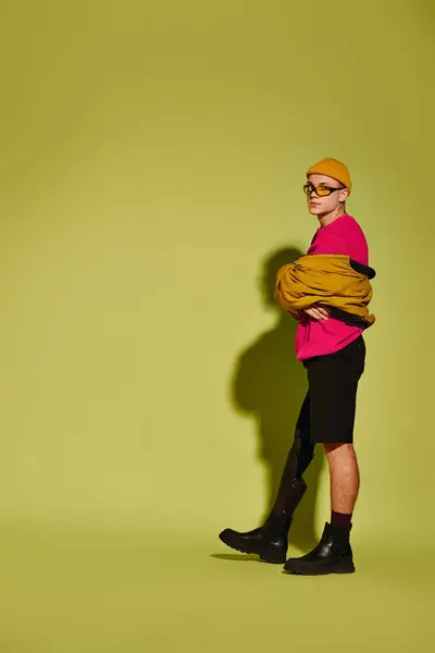 Um jovem bonito confiantemente posa em trajes elegantes contra um cenário verde arrojado. — Fotografia de Stock
