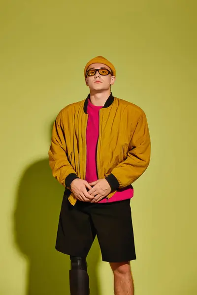 Bonito jovem posa confiantemente em trajes da moda, destacando sua perna protética em um estúdio. — Fotografia de Stock