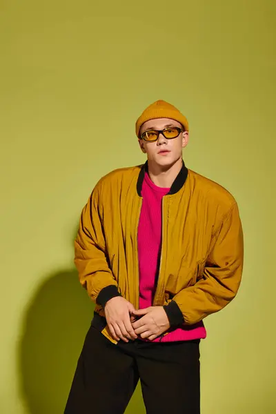 Handsome young man exudes charm while posing in a fashionable outfit against a bright background. — Stock Photo