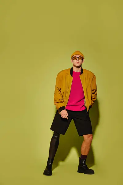 A young man in stylish clothes confidently showcases his prosthetic leg in a studio. — Stock Photo