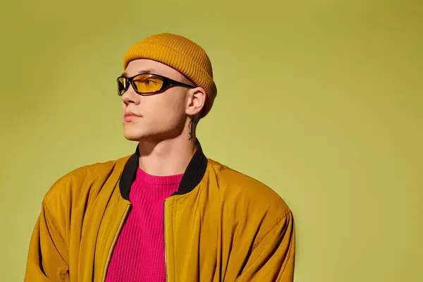 A fashion model stands confidently in a studio, wearing colorful attire and bold accessories. — Stock Photo