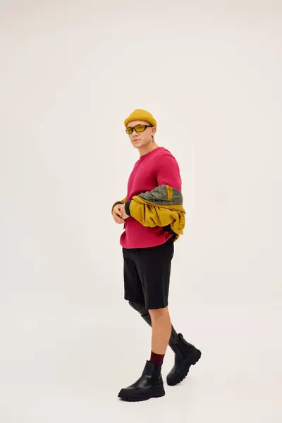 Um jovem bonito confiantemente posa em trajes na moda, destacando a inclusão e o estilo. — Fotografia de Stock