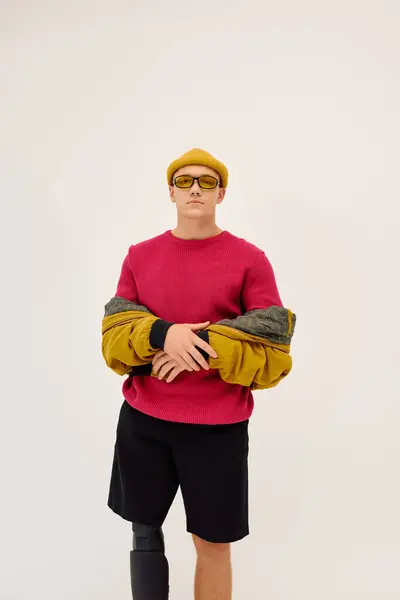 Young man with a prosthetic leg poses confidently in trendy clothing within a modern studio. — Stock Photo
