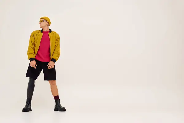 Um jovem com uma perna protética posa confiantemente em trajes da moda em um estúdio minimalista. — Fotografia de Stock