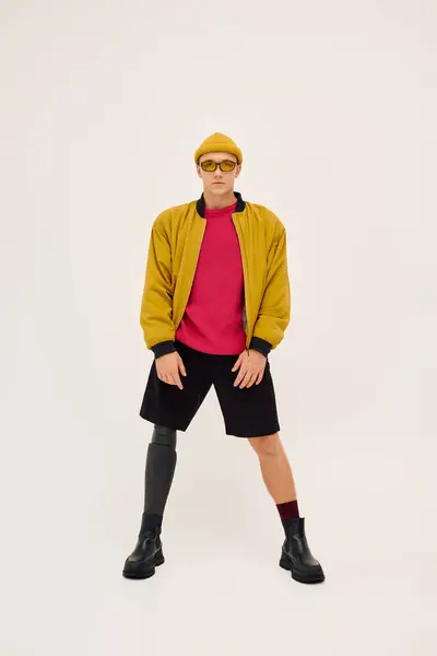 Un giovane uomo elegante posa con fiducia in un vestito alla moda in avanti, in mostra la sua gamba protesica. — Foto stock