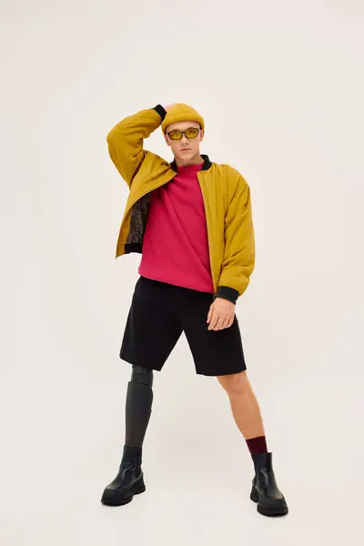 Un joven posa confiadamente con un atuendo moderno, destacando su pierna protésica en un elegante estudio. - foto de stock