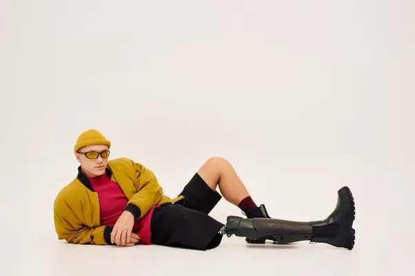 Bonito jovem lounges sem esforço em trajes de moda, destacando sua perna protética. — Fotografia de Stock