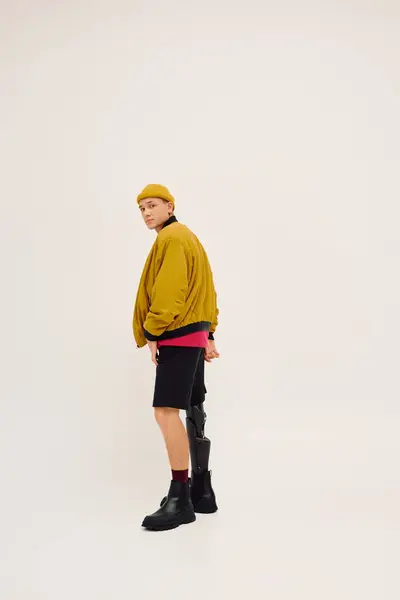 Um jovem com uma perna protética modela trajes na moda, incorporando estilo e confiança em um estúdio. — Fotografia de Stock