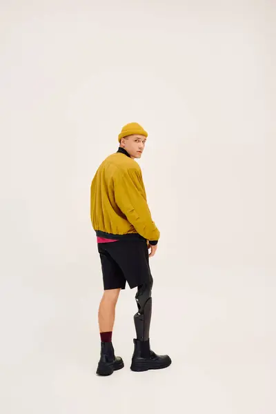 Handsome young man stands tall in trendy attire, highlighting his prosthetic leg with pride. — Stock Photo