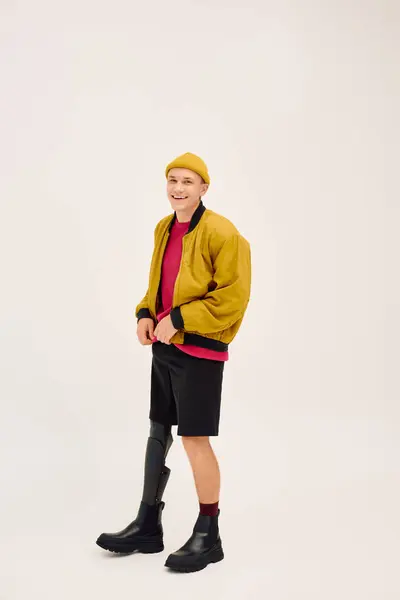 Bonito jovem confiantemente posa em trajes da moda enquanto abraça sua perna protética. — Fotografia de Stock
