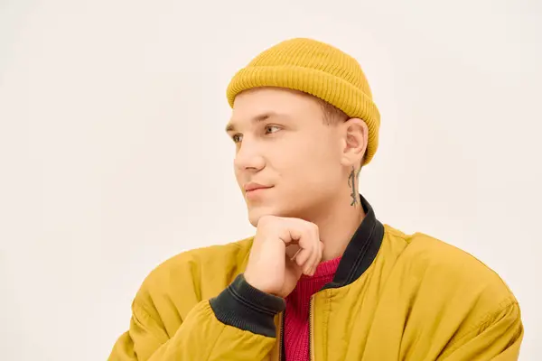 Un giovane uomo posa pensieroso con stile in uno studio vibrante, mettendo in evidenza le scelte di moda moderne. — Foto stock