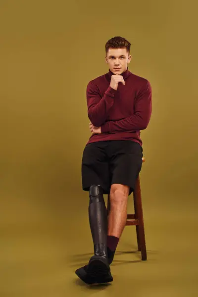 Um jovem elegante com uma perna protética posa confiantemente em trajes de moda em um estúdio. — Fotografia de Stock