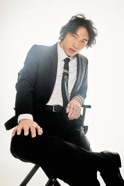 Young Asian male sits thoughtfully in a stylish outfit, embodying modern fashion trends. — Stock Photo