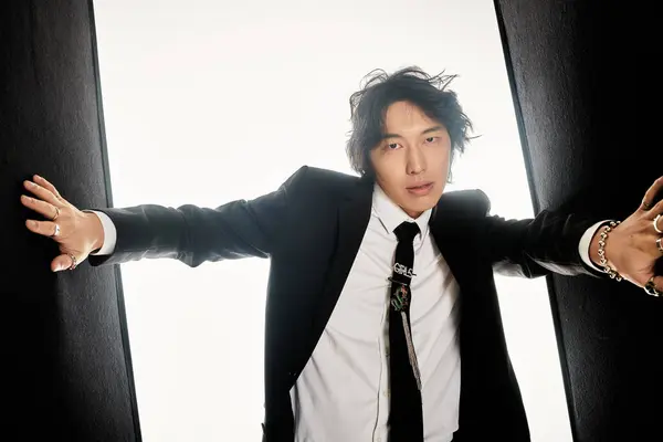 A stylish young man confidently poses in a modern outfit against a minimalist backdrop. — Stock Photo