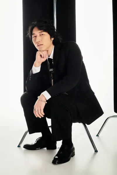 Stylish young man sits elegantly on a chair, exuding confidence and contemporary fashion vibes. — Stock Photo