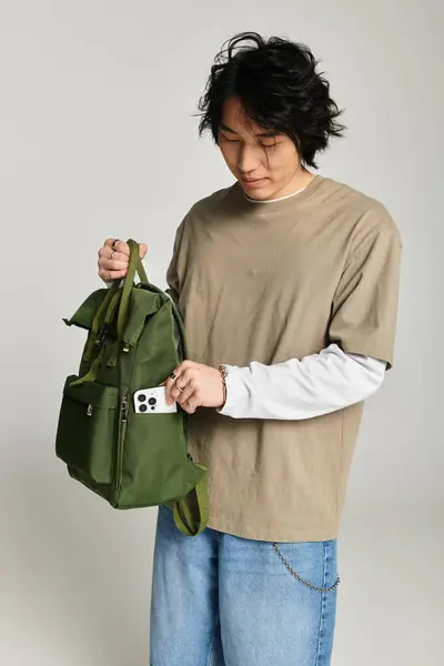 A handsome young asian man adjusts his backpack while getting ready for a day out in the city. — Stock Photo