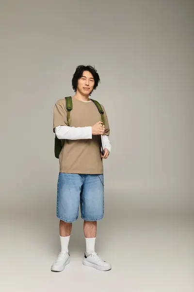 Stilvoller junger asiatischer Mann steht selbstbewusst da und strahlt eine mühelos coole Stimmung aus. — Stockfoto